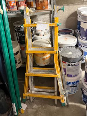 several buckets of paint and a ladder in a room