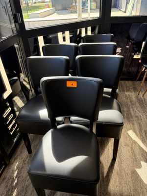 Plusieurs fauteuils en cuir noir sont alignés en rang devant une fenêtre