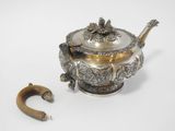 a silver teapot with a wooden handle next to it