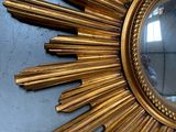 a gold sun mirror hanging on a wall in a room