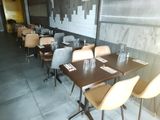 Dans un restaurant, des tables et des chaises sont alignées, avec un mur de briques en arrière-plan.