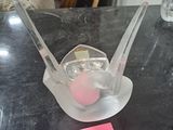 un objet en plastique posé sur une table, sur lequel est collé un autocollant rose