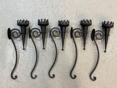 cinq appliques murales en fer forgé noir fixées sur un mur blanc