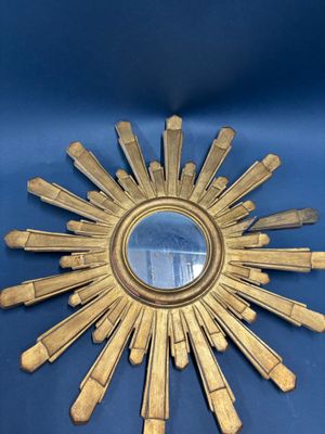 a gold starburst mirror on a blue surface
