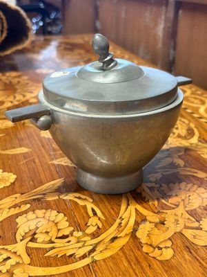 a silver pot sitting on a wooden table with a lid