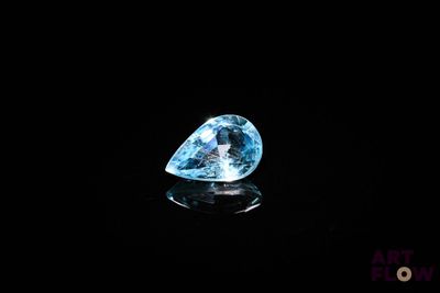 a blue diamond on a black surface with a reflection