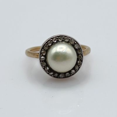a close up of a ring with a pearl and black diamonds