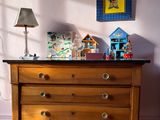 a dresser in the corner of a room with a lamp on it