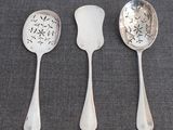 three silver spoons and a spoon with a flower design on them