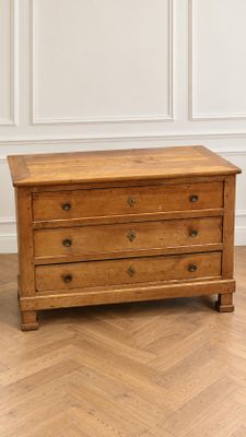 une commode en bois posée sur un parquet dans une pièce
