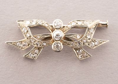 une image représentant une broche en forme de nœud en or sertie de diamants