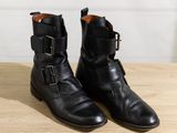 pair of black leather boots with buckles on a wooden table