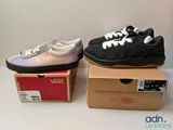 deux paires de baskets Vans posées sur des cartons, sur une table