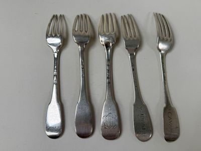 four forks are lined up on a white surface with silverware on them
