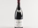 a bottle of red wine sitting on top of a white table