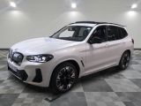 Le SUV BMW blanc est garé sur un sol carrelé à damier.