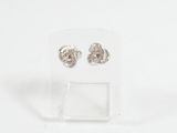 une paire de boucles d'oreilles en argent posée sur un présentoir transparent