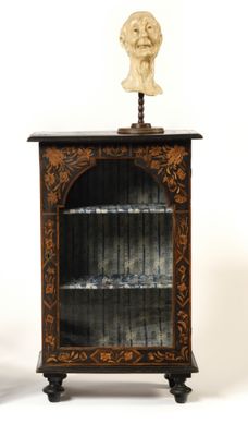 a small cabinet with a bust on top of it
