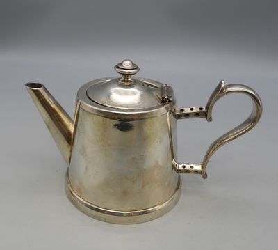 an antique silver teapot with a handle on a white surface