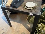 une petite table sur laquelle se trouve une horloge, dans une pièce