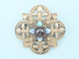 a gold brooch with a purple stone in the center
