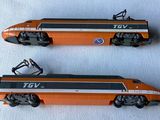 two toy trains sitting side by side on a white surface
