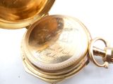 a gold pocket watch sitting on a white surface