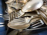 a lot of silver spoons and forks in a blue container