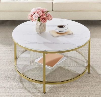 La table basse est dotée d'un plateau en verre et d'un piètement doré.