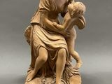 une statue ancienne représentant une femme tenant un enfant dans ses bras, posée sur un socle en marbre