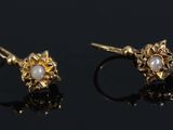 a pair of gold and pearl earrings on a black surface