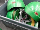 some green hard hats are sitting in a bin on the floor