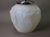 a white glass vase with a silver lid on a table