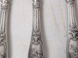 four silverplated knives and a knife on a white surface