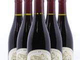 quatre bouteilles de vin rouge sont alignées sur une surface blanche