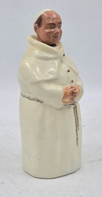 une figurine représentant un homme vêtu d'une robe blanche et tenant une canne