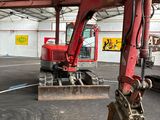 une pelleteuse rouge qui se trouve à l'intérieur d'un bâtiment