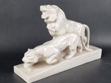 a white statue of a lion and a lioness on a marble base