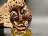 two wooden masks that are on display on a table