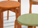 three wooden stools with different colored tops sit in a row