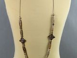 un torse de mannequin portant un collier composé de perles en métal et en verre