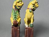 pair of yellow and green foo foo foo figurines sitting on top of a wooden box