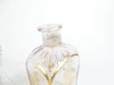 a clear glass bottle with a gold design on it