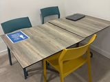 une table et deux chaises dans une pièce où est accrochée une pancarte au mur