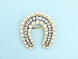 a close up of a pearl and diamond broochle on a blue background