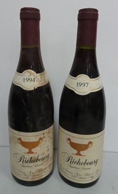 two bottles of red wine sitting next to each other on a table