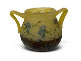 yellow vase with blue flowers on it sitting on a white surface