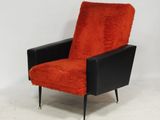 une chaise orange et noire, avec des pieds noirs, devant un mur blanc