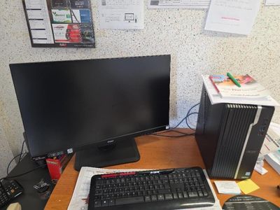 a computer desk with a monitor, keyboard, mouse and other items on it