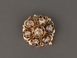 un gros plan d'une broche en or et diamants posée sur une surface grise